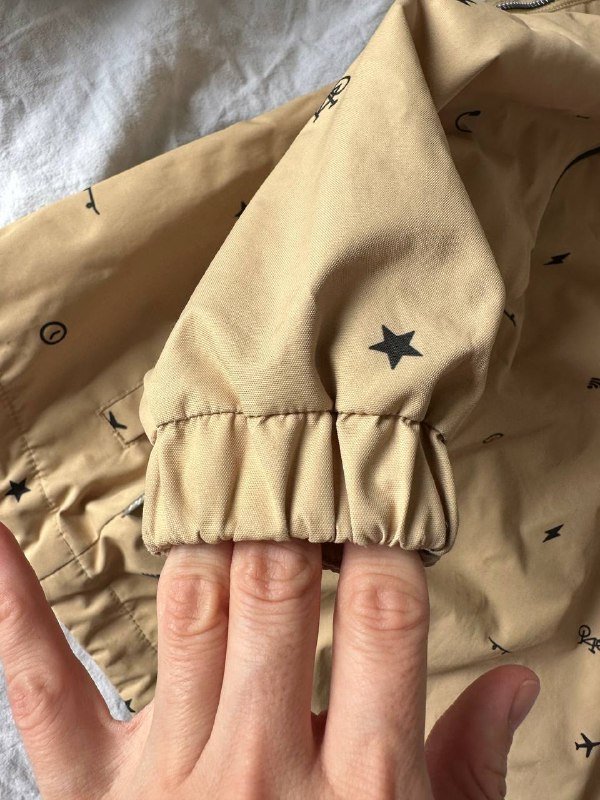 Куртка бежевого цвета с рисунком звезд и символов